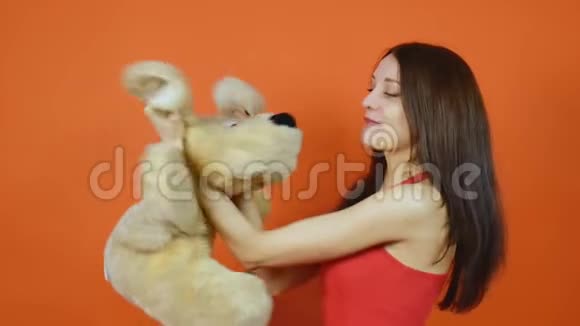 漂亮的棕色头发的年轻女孩和一只毛绒白色的狗玩情感一幅橙色画室里的画视频的预览图