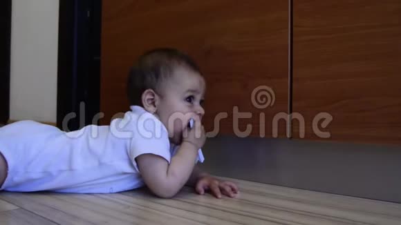 可爱的六个月大的牙齿男孩把衣服钉在嘴里视频的预览图