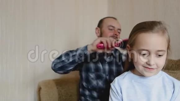 爸爸坐在沙发上梳女儿头发爸爸和女儿花时间在一起视频的预览图