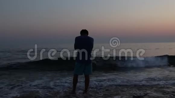 日落时海滩上悲伤沮丧的男人剪影视频的预览图