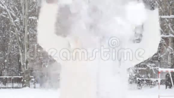美丽的冬日女孩在寒冷的冬日公园里吹雪在户外飞舞的雪花视频的预览图