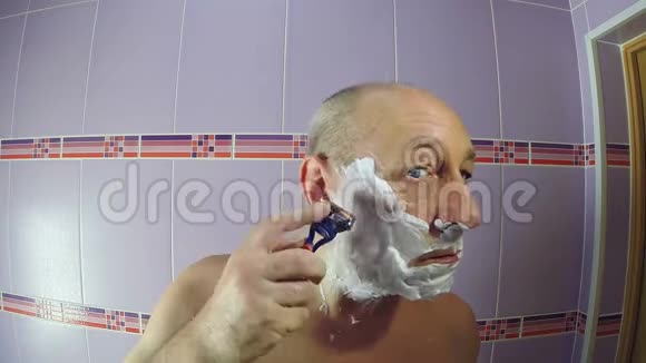 浴室里的一个人用剃刀剃掉鬓角上的胡茬视频的预览图