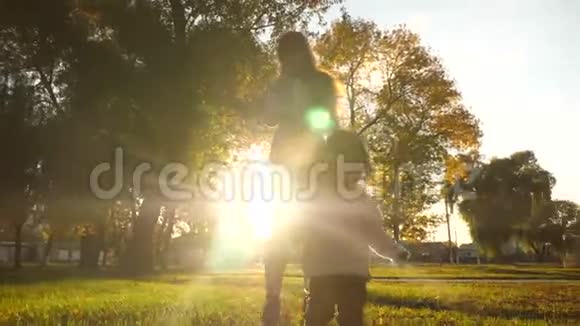 母亲和她的小女儿在夕阳的照耀下在公园里散步妈妈照顾玩耍的孩子视频的预览图