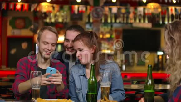 一群多民族的朋友在酒吧里休息朋友们在酒吧的电话里拍照在酒吧里共用一张照片视频的预览图