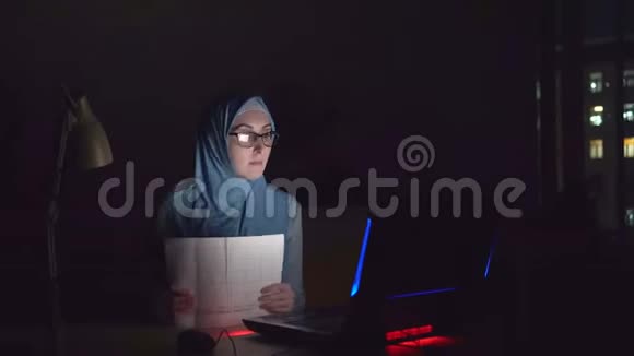 办公室里戴着眼镜和头巾的疲惫的穆斯林女孩在加班视频的预览图