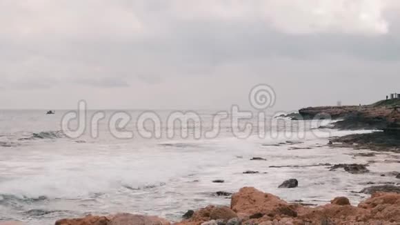 美丽的地中海大岩石海滩巨大的海浪撞击岩石海岸海浪创造泡沫和飞溅SS视频的预览图