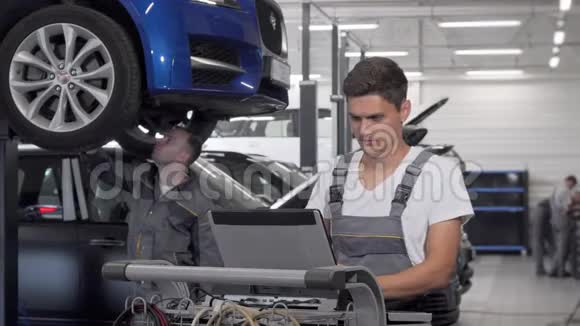 年轻的汽车修理工在车库里用笔记本电脑视频的预览图