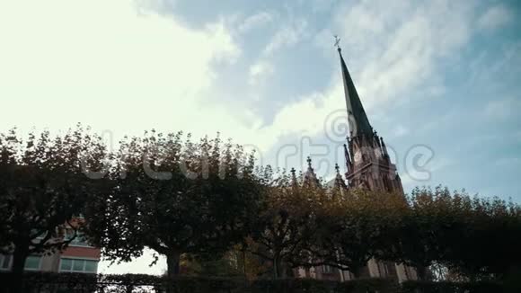 哥特式风格的旧教堂有尖顶和时钟前景是树木视频的预览图