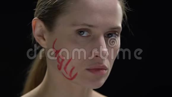 坚定的女人在脸上抹丑陋的字对抗社会舆论视频的预览图