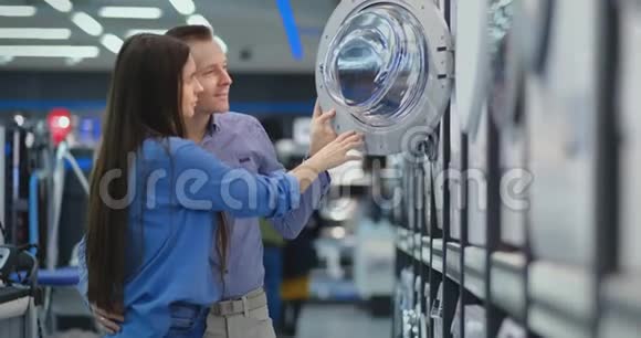 美丽的男人和女人选择现代智能洗衣机在消费电子商店为他们的新的现代家居视频的预览图