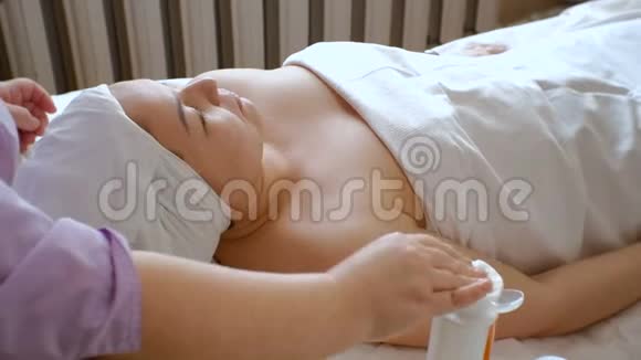 美容师的手湿润了棉垫一个美容院里的亚洲女孩躺在沙发上清洗和r的过程视频的预览图