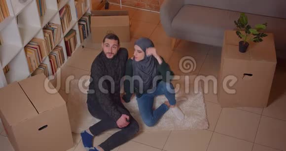 一对年轻快乐的穆斯林夫妇坐在一间新买的公寓里幸福地微笑着拍摄特写镜头视频的预览图