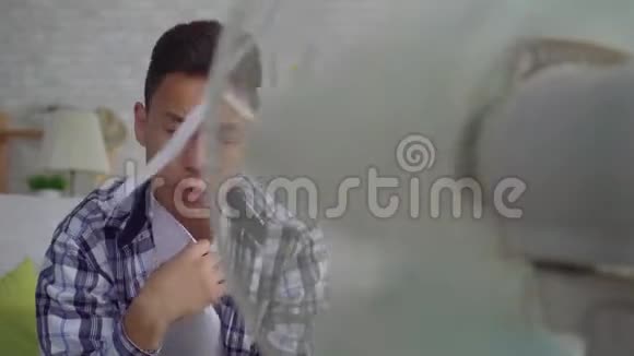 年轻的亚洲男人从坐在工作风扇前的热气中拯救出来的热量概念视频的预览图