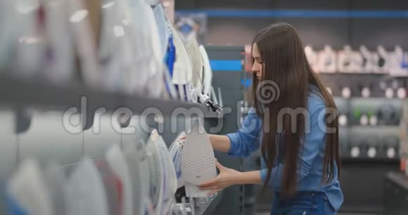 一个年轻漂亮的黑发女人在商店里检查一个熨斗来买一套新公寓视频的预览图