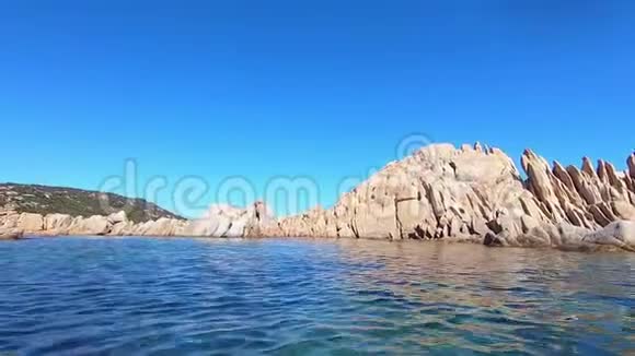 在清澈的大海和蓝天中间的撒丁岛典型的粉红色花岗岩岩石团的水位上拍摄视频的预览图