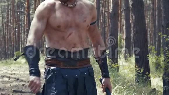 靠近一个野蛮战士的身体手中拿着两把斧头在森林里视频的预览图