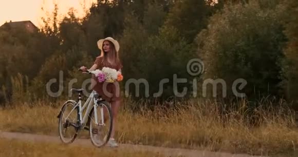 夏天在田野里女孩带着鲜花和帽子骑着自行车上路视频的预览图
