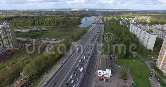从空中俯瞰一条一望无际的高速公路在绿色的城市风景中繁忙的交通视频的预览图