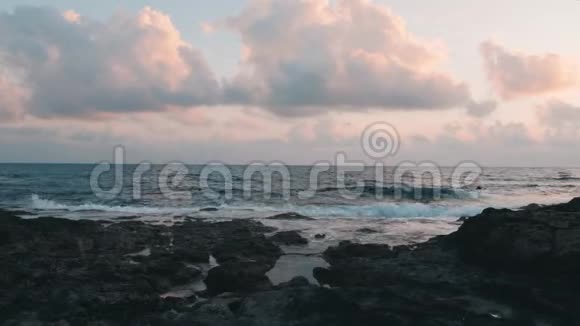 黄昏时美丽的岩石海岸巨大的海浪冲击着岩石海岸狂风巨浪到达岸边暴风海美丽的夜晚视频的预览图