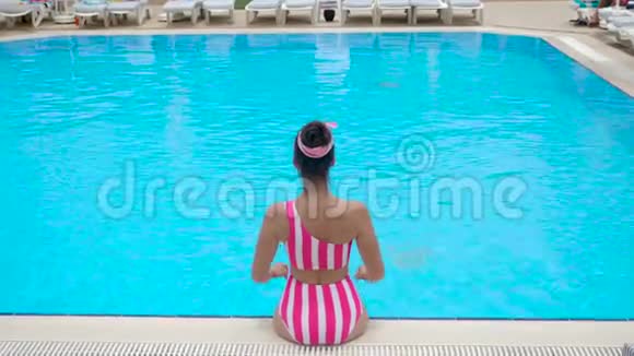 穿着时髦条纹泳衣的性感年轻女子坐着视频的预览图