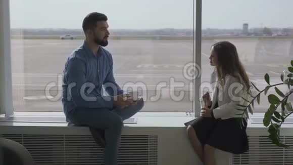 成年白种人男人和小女孩坐在机场窗台上聊天父女在等待视频的预览图
