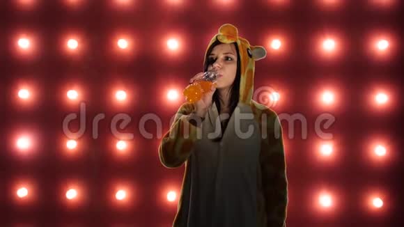女人从瓶子里喝汽水穿着亮晶晶的孩子的女人袋鼠式的睡衣情感肖像视频的预览图