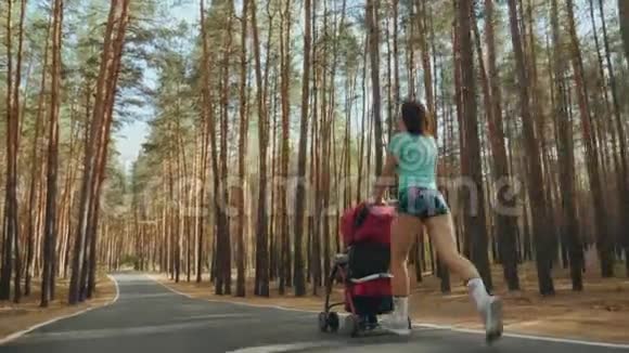 在森林里的路上带着婴儿车奔跑的女人视频的预览图
