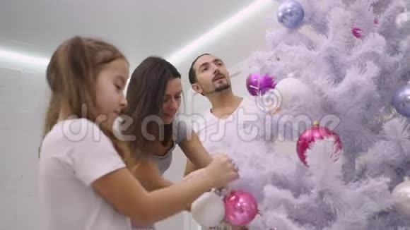 家庭在客厅里用五颜六色的花束装饰圣诞树的视频视频的预览图