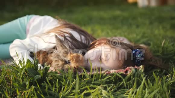 小女孩躺在绿草上拥抱一只棕色的兔子视频的预览图