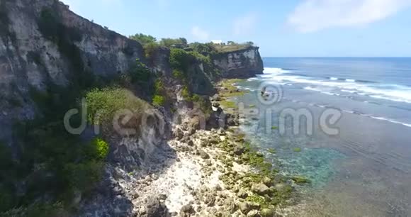 鸟瞰岩石海岸线风景秀丽的海洋与飞溅的波浪上午在印尼巴厘岛热带无人机景观视频的预览图