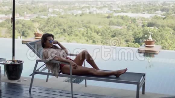 躺在酒店游泳池露台顶上的躺椅上的女人视频的预览图