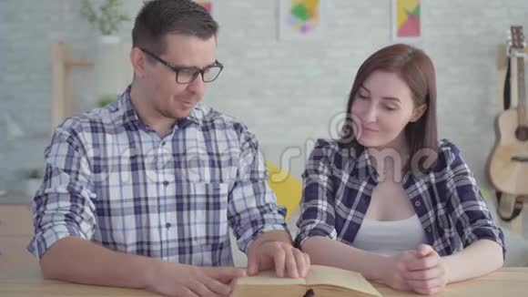 一对年轻夫妇在一间现代化的公寓里看书学习视频的预览图