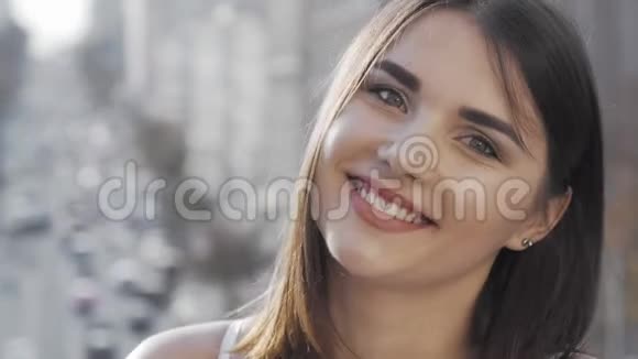 可爱的年轻快乐的女人对着镜头微笑背景是城市的街道视频的预览图