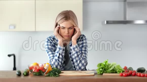 悲伤的年轻家庭主妇在厨房做健康的新鲜沙拉时头痛视频的预览图