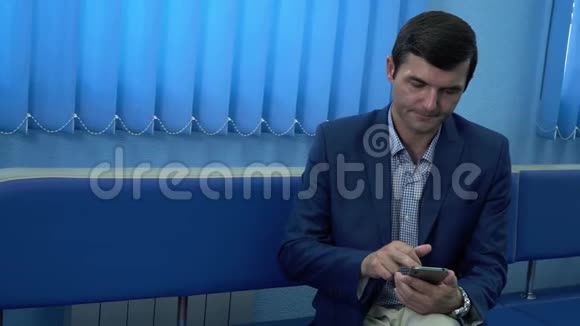 这个成年人坐在现代私人诊所的走廊里用手机等待他的分析结果视频的预览图