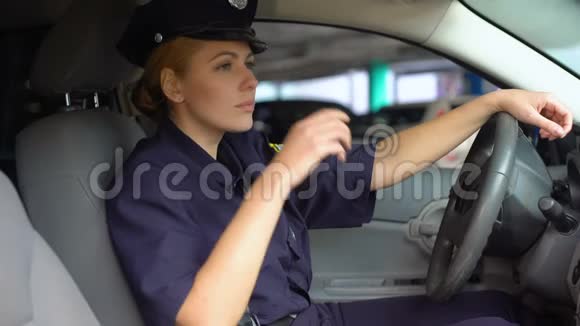 疲惫的女警察戴着服务帽坐在巡逻车上夜班视频的预览图
