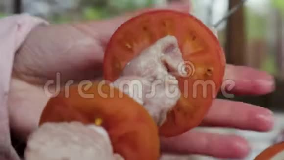 女人手把猪肉西红柿和洋葱放在镀铬烤架上视频的预览图