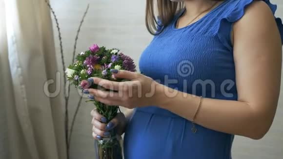 一个年轻的孕妇闻着一朵花摸着肚子视频的预览图