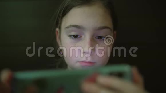 夜间拍摄的孩子的青少年女孩脸浏览平板电脑或智能手机上的光反射关门视频的预览图