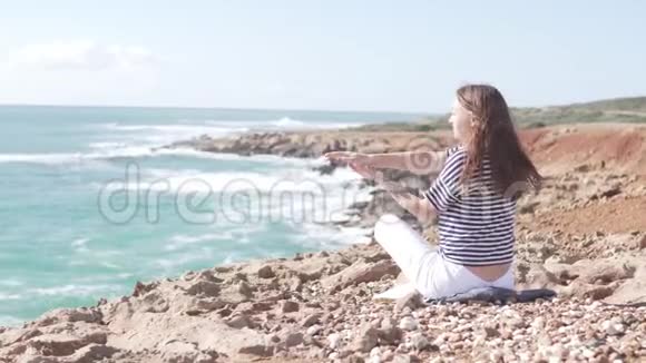 在海边岩石上美丽的地方做体操的游客视频的预览图
