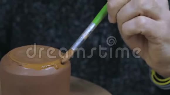 陶工用刷子给水壶上油以固定盖子手工陶土茶壶用于茶道棕色陶瓷茶壶4k视频的预览图