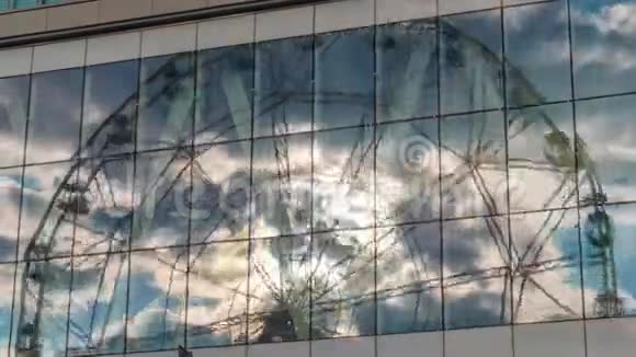 时差日落时玻璃墙上的云和摩天轮的反射视频的预览图