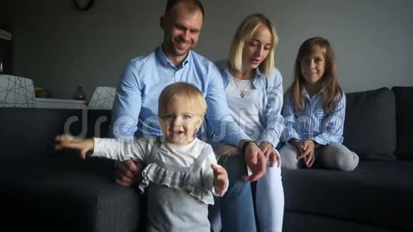 年轻的父母丈夫和妻子还有他们的两个女儿都穿着牛仔服开心地笑着家庭幸福视频的预览图