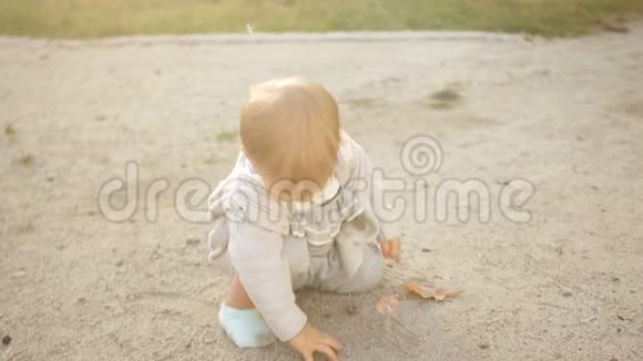 可爱的小女孩在沙滩上玩耍嘴里衔着一颗小石子为人父母快乐的童年视频的预览图