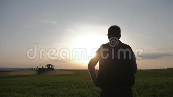 年轻的农民正在看农场拖拉机在日落时喷洒喷雾器除草剂和杀虫剂视频的预览图