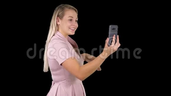 穿着粉红色裙子的女性用她的智能手机打视频电话阿尔法频道视频的预览图