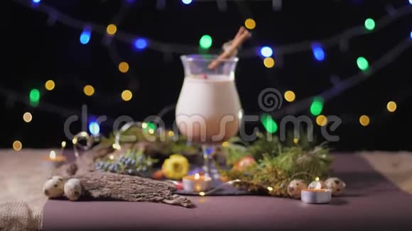 美丽的鸡尾酒杯在圣诞树和灯光的背景下带有传统的鸡蛋饮料季节蛋酒视频的预览图