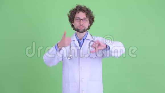 困惑的年轻留胡子的医生在竖起大拇指和竖起大拇指之间做出选择视频的预览图