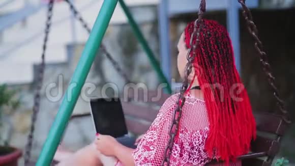 年轻的女性自由职业者正在用一台电脑在秋千上工作视频的预览图