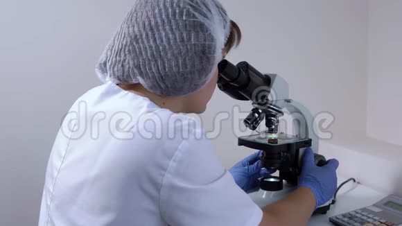实验室里的女化学家用显微镜工作视频的预览图